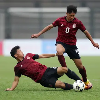 Two soccer players mid-tackle, one sliding and the other jum