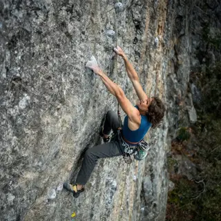 A rock climber clinging to a cliff face with arms and legs e