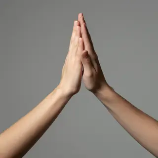Two people doing a high-five, palms meeting with all fingers