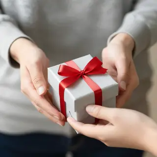 One person handing a small gift box to another person, both 