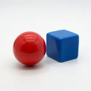 A red ball and a blue cube sitting side by side on a white s