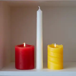 A tall thin white candle, a short fat red candle, and a medi