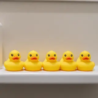 Exactly 5 yellow rubber ducks sitting in a row on a bathroom