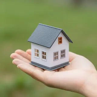A miniature house sitting on the palm of someone's hand