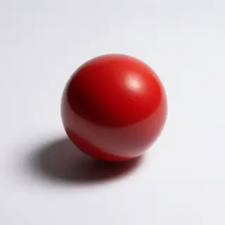 A red sphere on a white surface with a single shadow cast to