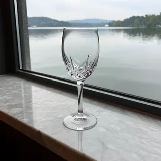 A crystal wine glass on a polished marble counter next to a 
