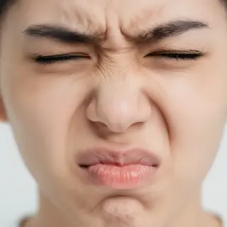 A close-up of a person's face showing clear disgust, nose wr