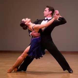 Two tango dancers in a close embrace, the man dipping the wo