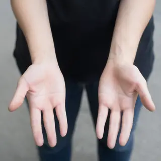 A person standing with both hands visible at their sides, fi