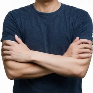A man with arms crossed, both hands resting on opposite uppe