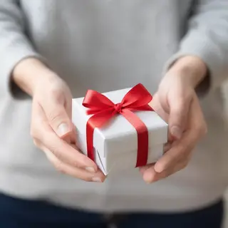 One person handing a small gift box to another person, both 