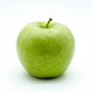 A ripe green apple on a seamless white background with soft 