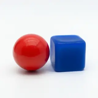 A red ball and a blue cube sitting side by side on a white s