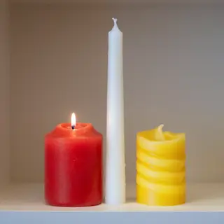A tall thin white candle, a short fat red candle, and a medi