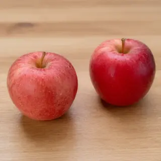 Exactly 3 red apples arranged on a wooden table