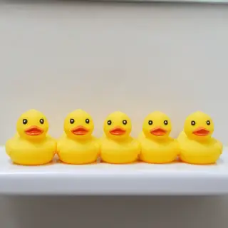 Exactly 5 yellow rubber ducks sitting in a row on a bathroom