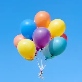 Exactly 11 colorful balloons floating against a clear blue s