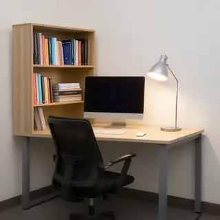 An office workspace with a desk, chair, bookshelf, and lamp 