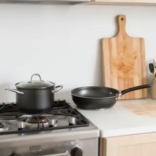 A kitchen with pots, pans, a stove, and a cutting board but 
