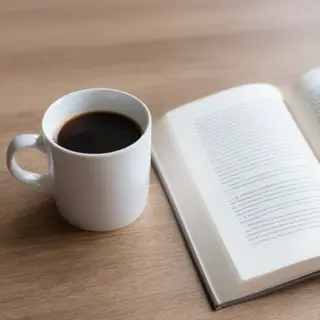 A coffee mug next to an open book on a desk