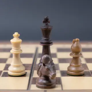 Five chess pieces on a board: a king in the center, a queen 