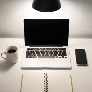 A desk scene: laptop in the center, coffee mug to the left, 