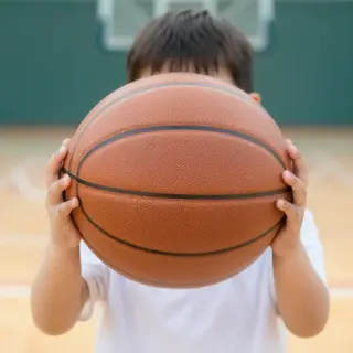 A child holding a basketball, both at correct relative sizes