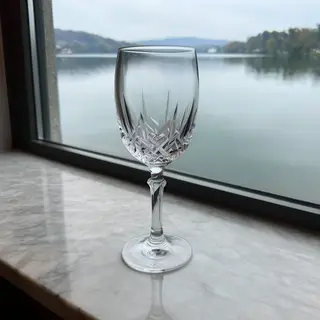 A crystal wine glass on a polished marble counter next to a 