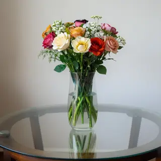 A vase of flowers on a glass table with a clear reflection v