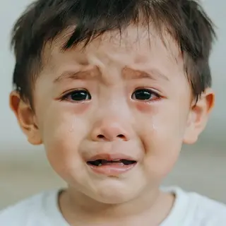 A 5-year-old child with round cheeks and large eyes, crying 
