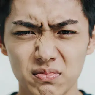 A close-up of a person's face showing clear disgust, nose wr