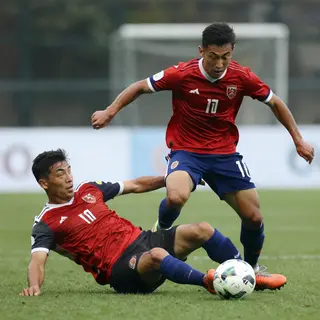Two soccer players mid-tackle, one sliding and the other jum