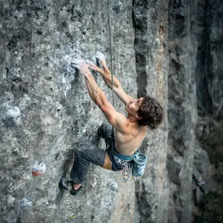 A rock climber clinging to a cliff face with arms and legs e