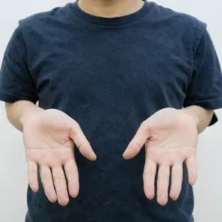 A person standing with both hands visible at their sides, fi