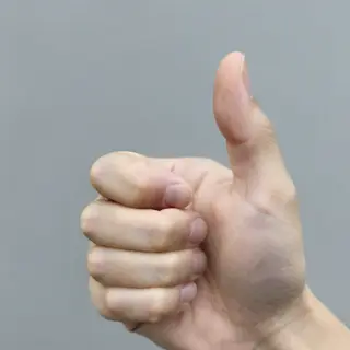 A hand giving a thumbs-up with four fingers curled and thumb