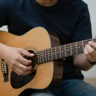 A person playing an acoustic guitar with left hand on the fr