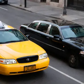 A yellow taxi and a black limousine parked next to each othe