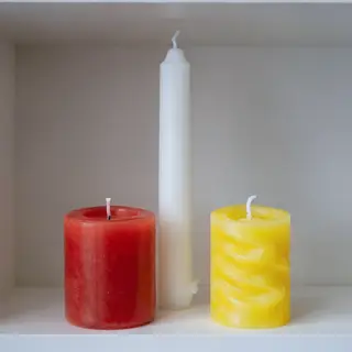 A tall thin white candle, a short fat red candle, and a medi
