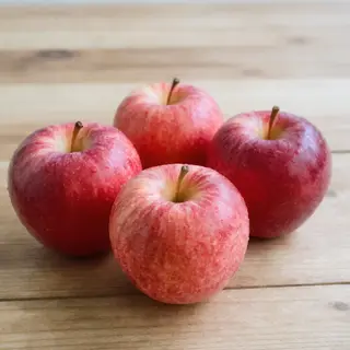 Exactly 3 red apples arranged on a wooden table