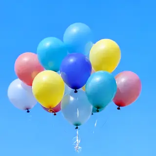 Exactly 11 colorful balloons floating against a clear blue s