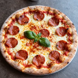 A pepperoni pizza with tomato sauce, basil, and crust but ab