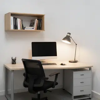 An office workspace with a desk, chair, bookshelf, and lamp 