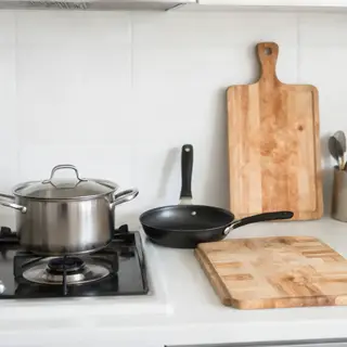 A kitchen with pots, pans, a stove, and a cutting board but 