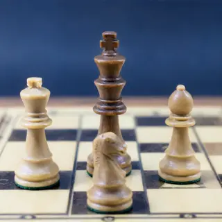 Five chess pieces on a board: a king in the center, a queen 