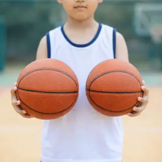 A child holding a basketball, both at correct relative sizes