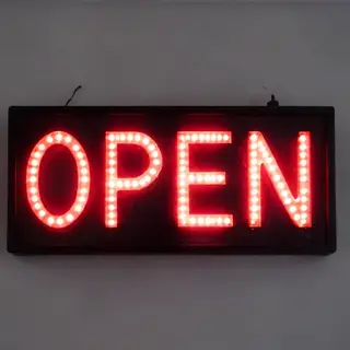 The word 'OPEN' displayed on a red LED sign with glowing pix