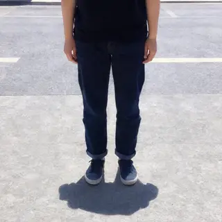 A person standing outdoors at midday with a short shadow dir
