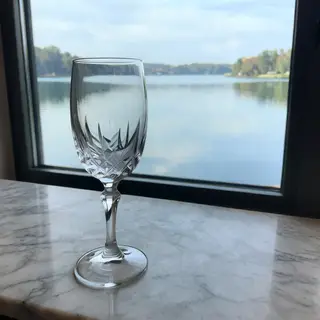 A crystal wine glass on a polished marble counter next to a 