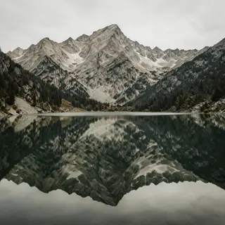 A mountain range reflected in a still alpine lake, with the 