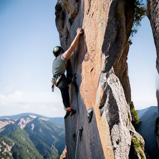 A rock climber clinging to a cliff face with arms and legs e